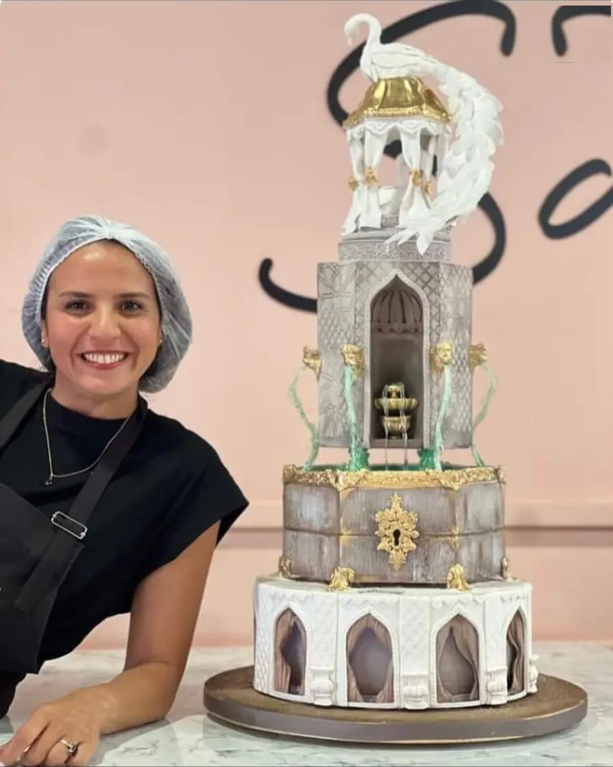 La cheffe de Gâteaux Régal devant une pièce montée orientale au cygne doré